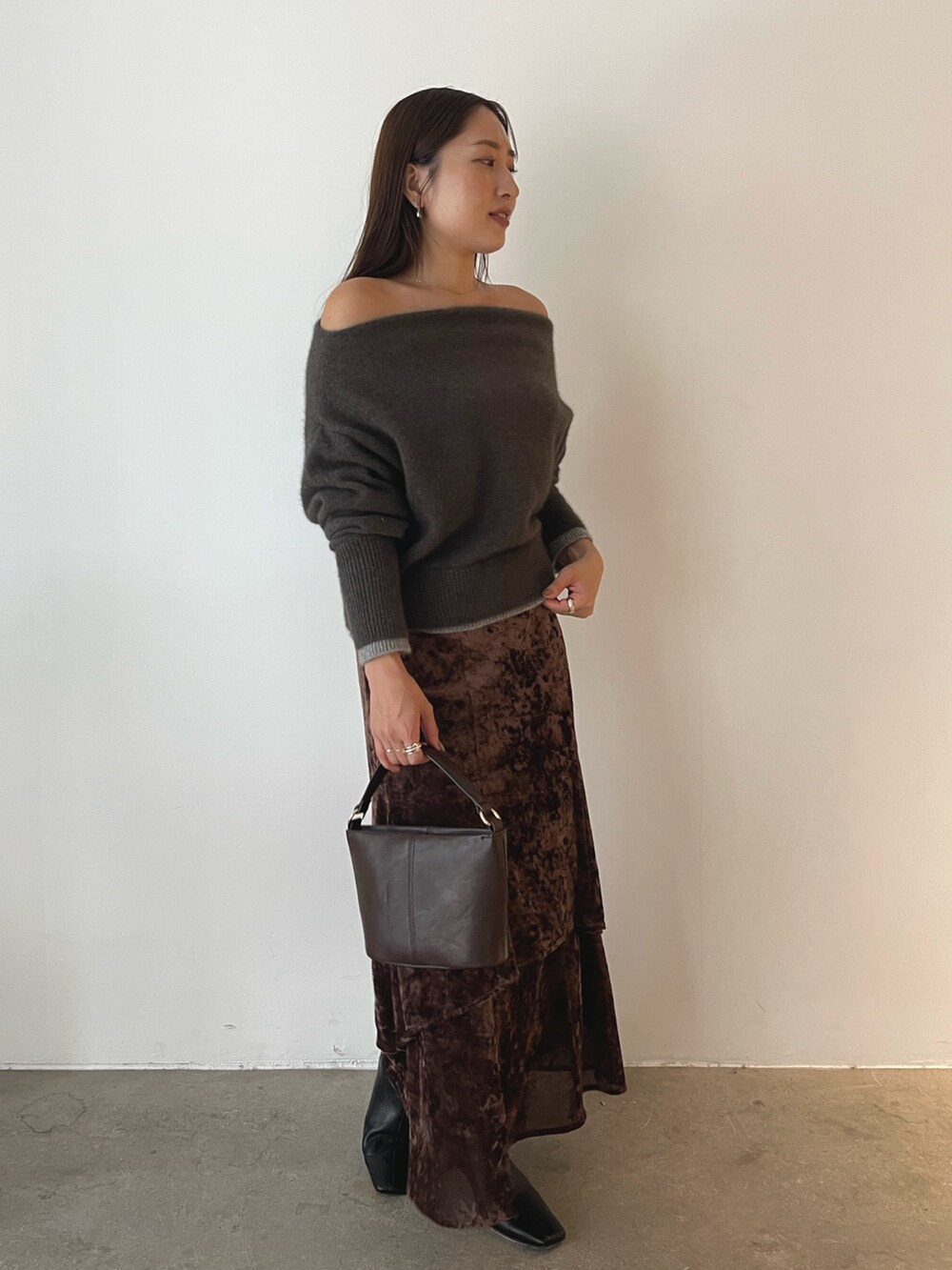ブラウン系のハンドバッグ、ブラウン系のニット/セーター、ブラウン系のスカートを着用したレディースの秋コーディネートの2枚目の写真