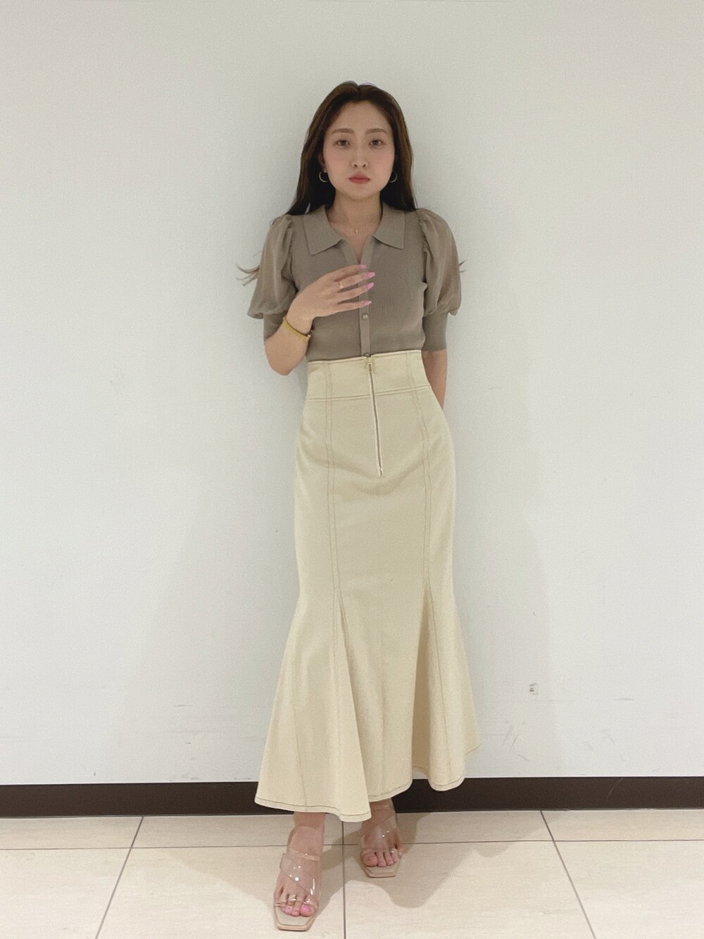 ホワイト系のスカート、その他のサンダル、ブラウン系のニット/セーターを着用したレディースの春コーディネートの2枚目の写真