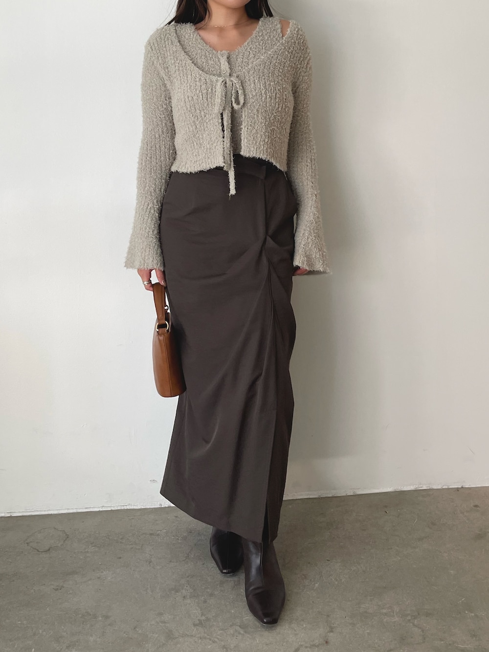 グレー系のアンサンブル、イエロー系のハンドバッグ、ブラウン系のスカートを着用したレディースの秋コーディネートの3枚目の写真