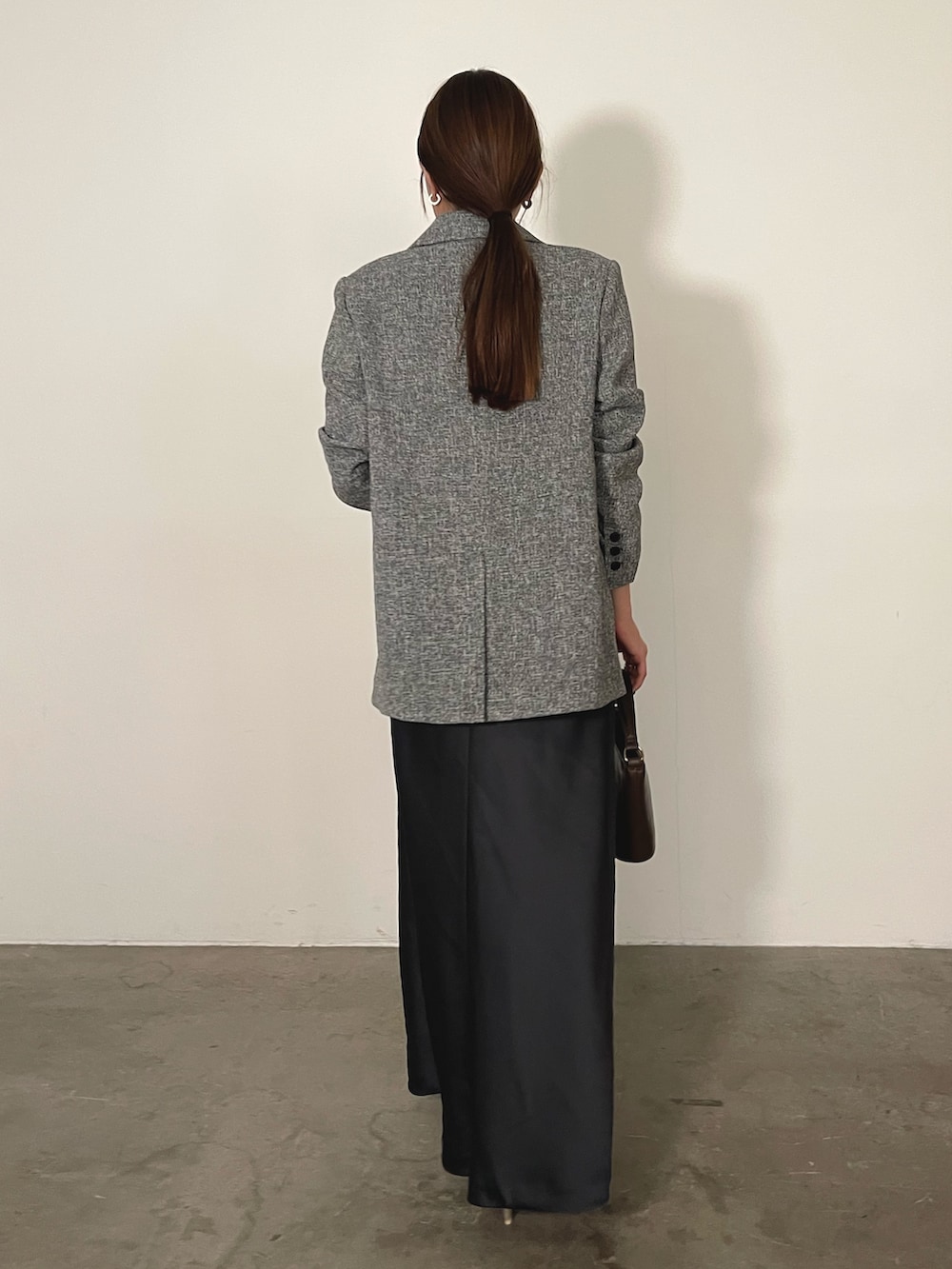 グレー系のドレス、ブラウン系のハンドバッグ、ゴールド系のパンプスを着用したレディースの冬コーディネートの6枚目の写真