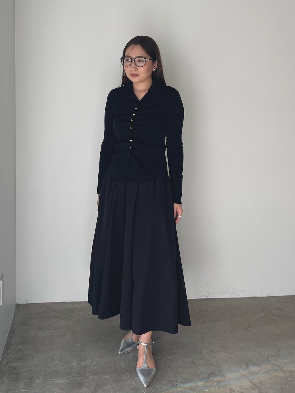 シルバー系のパンプス、ブラック系のワンピース、ゴールド系のピアス（両耳用）を着用したレディースの冬コーディネートの2枚目の写真