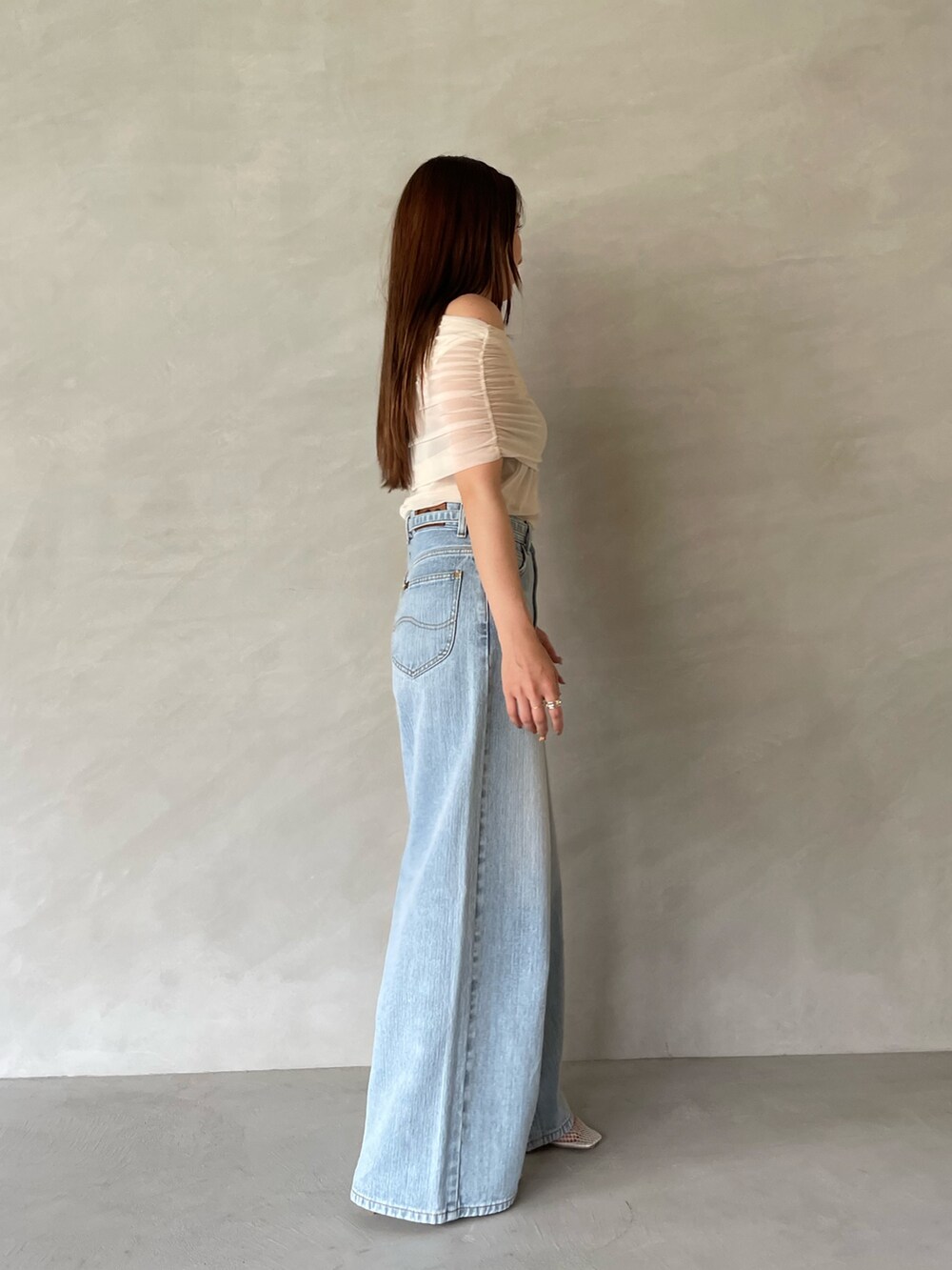 ブルー系のデニムパンツ、ホワイト系のTシャツ/カットソー、ホワイト系のサンダルを着用したレディースの夏コーディネートの5枚目の写真