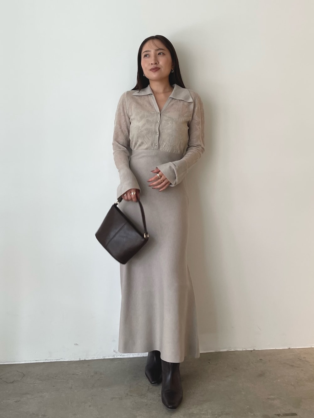 ブラウン系のハンドバッグ、ベージュ系のワンピース、ブラウン系のブーツを着用したレディースの秋コーディネートの2枚目の写真