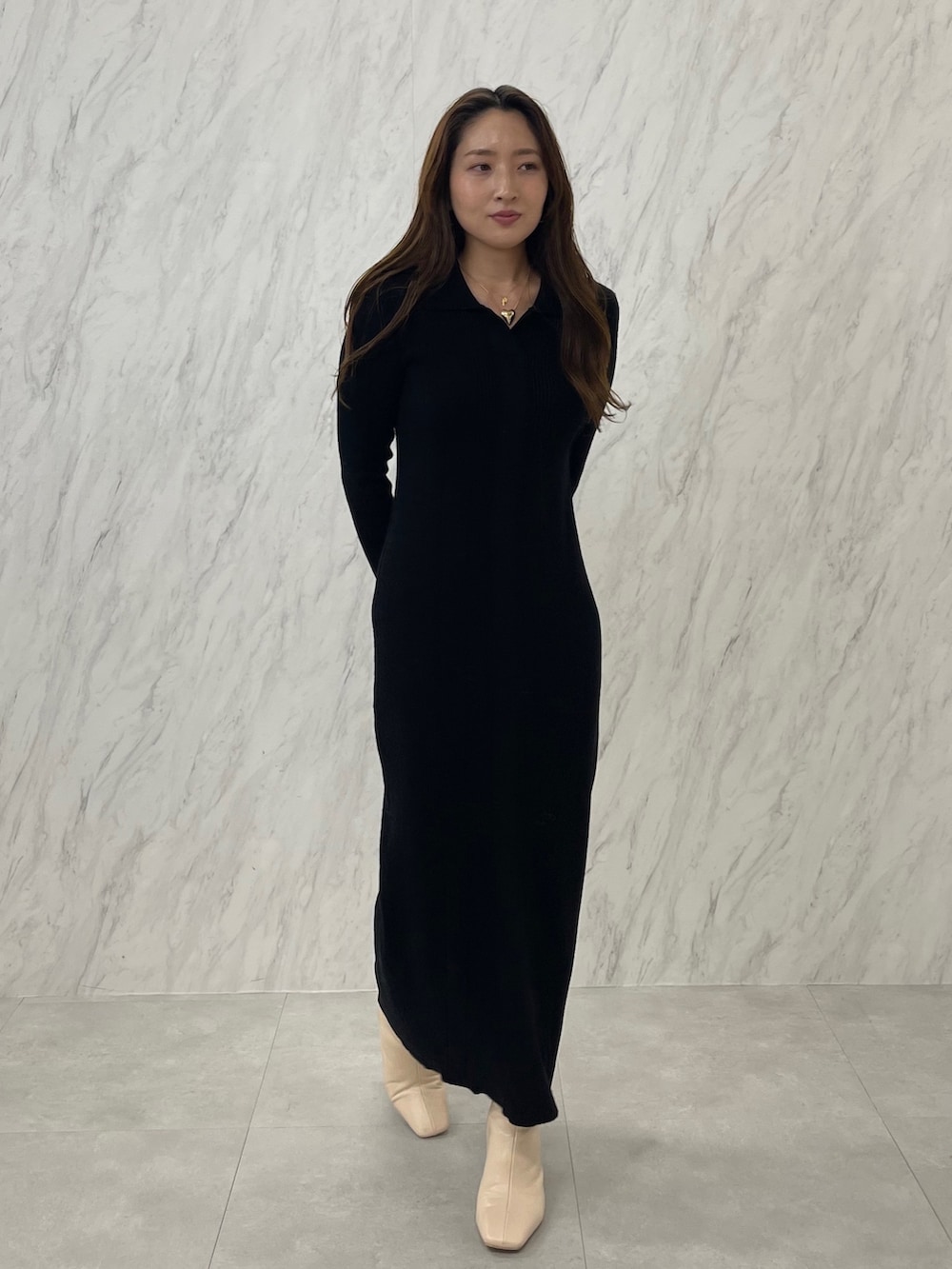 ブラック系のワンピース、ホワイト系のブーツ、ゴールド系のネックレスを着用したレディースの冬コーディネートの2枚目の写真