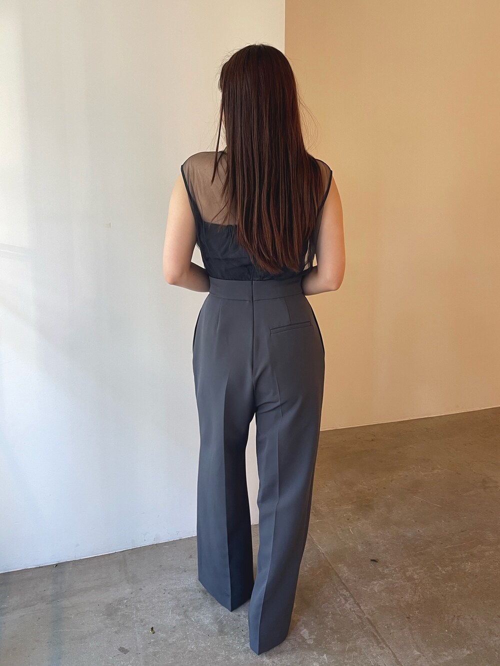 シルバー系のパンプス、グレー系のパンツドレス、ゴールド系のピアス（両耳用）を着用したレディースの夏コーディネートの4枚目の写真