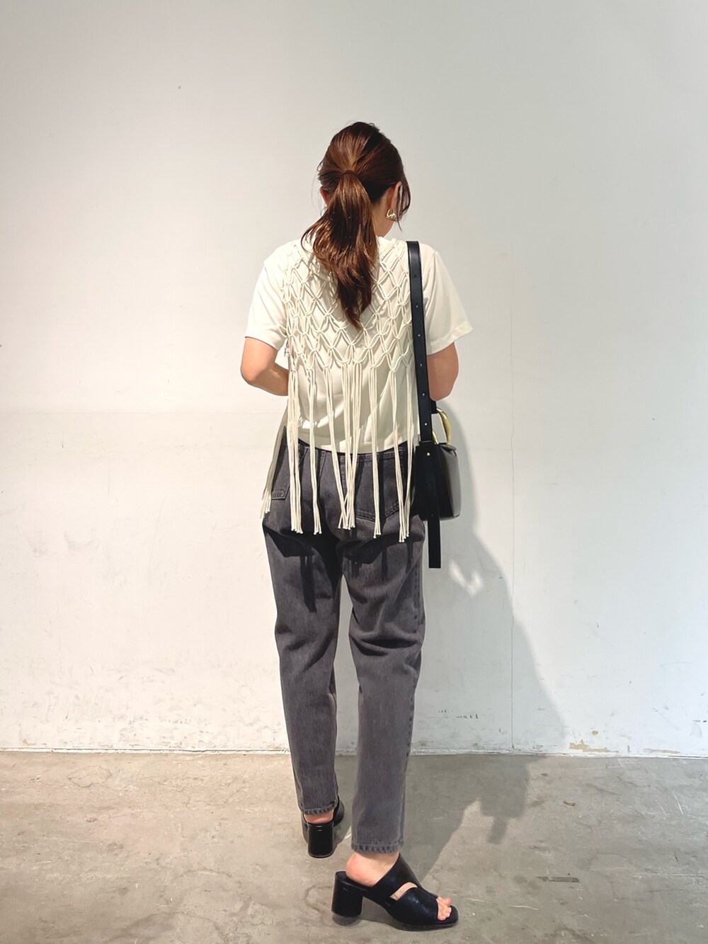 ブラック系のデニムパンツ、ブラック系のサンダル、ブラック系のショルダーバッグを着用したレディースの春コーディネートの4枚目の写真