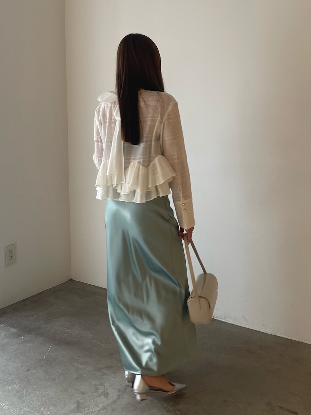 シルバー系のパンプス、ホワイト系のシャツ/ブラウス、グリーン系のスカートを着用したレディースの冬コーディネートの6枚目の写真