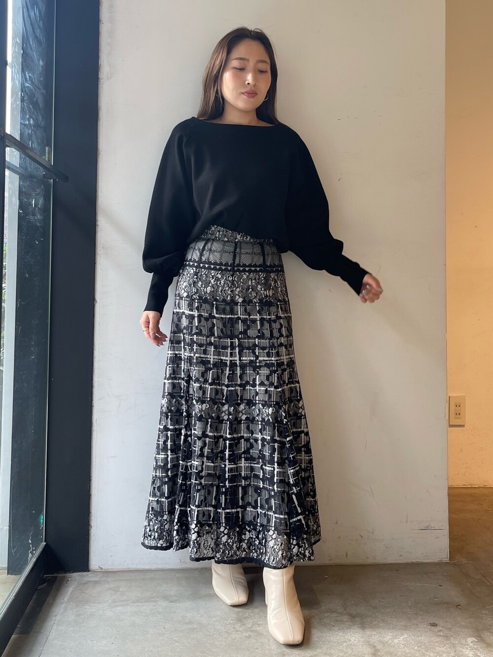 ブラック系のニット/セーター、ホワイト系のブーツ、ブラック系のスカートを着用したレディースの冬コーディネートの3枚目の写真