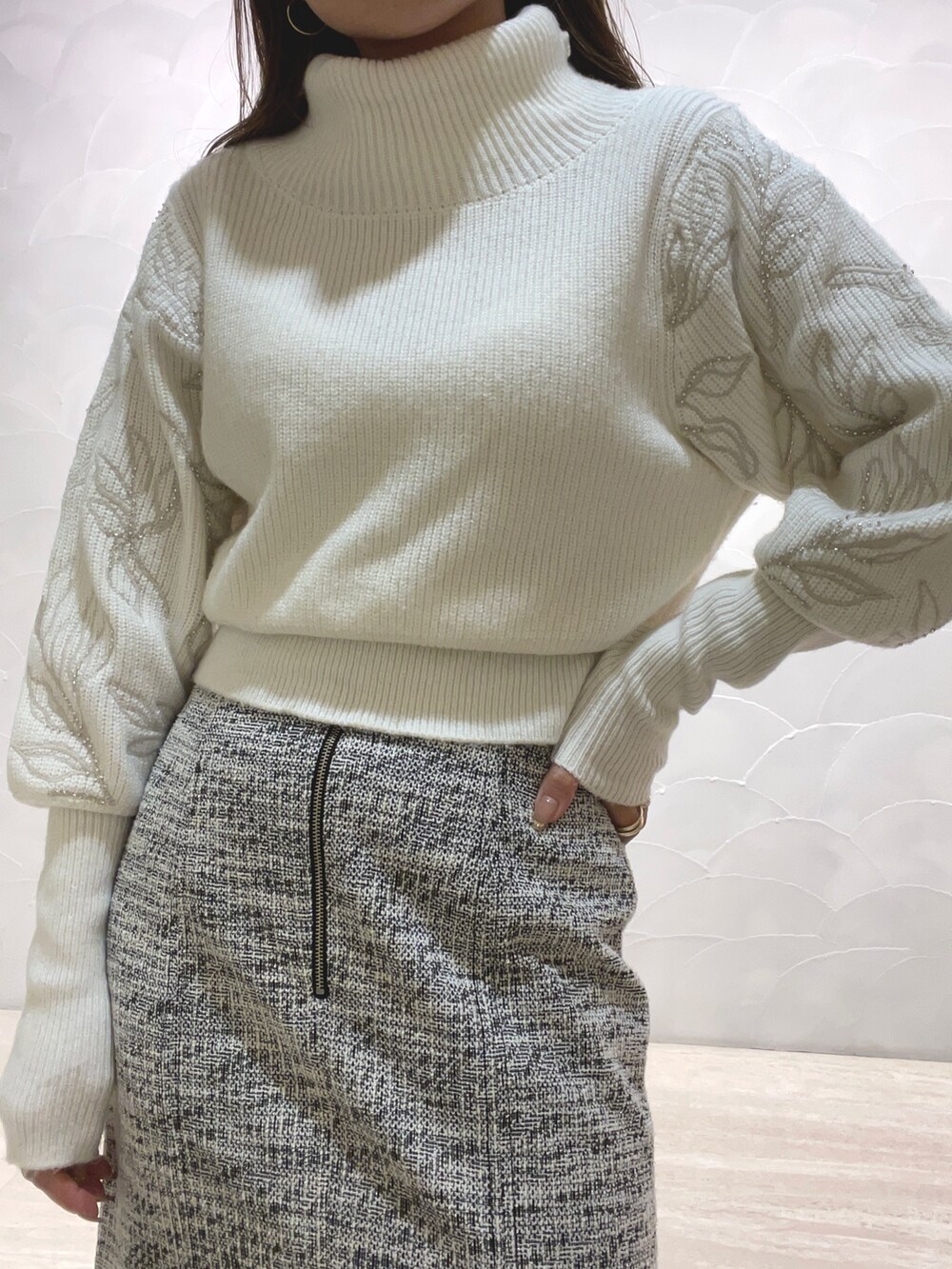 ホワイト系のニット/セーター、ブラック系のスカート、ベージュ系のブーツを着用したレディースの秋コーディネートの6枚目の写真