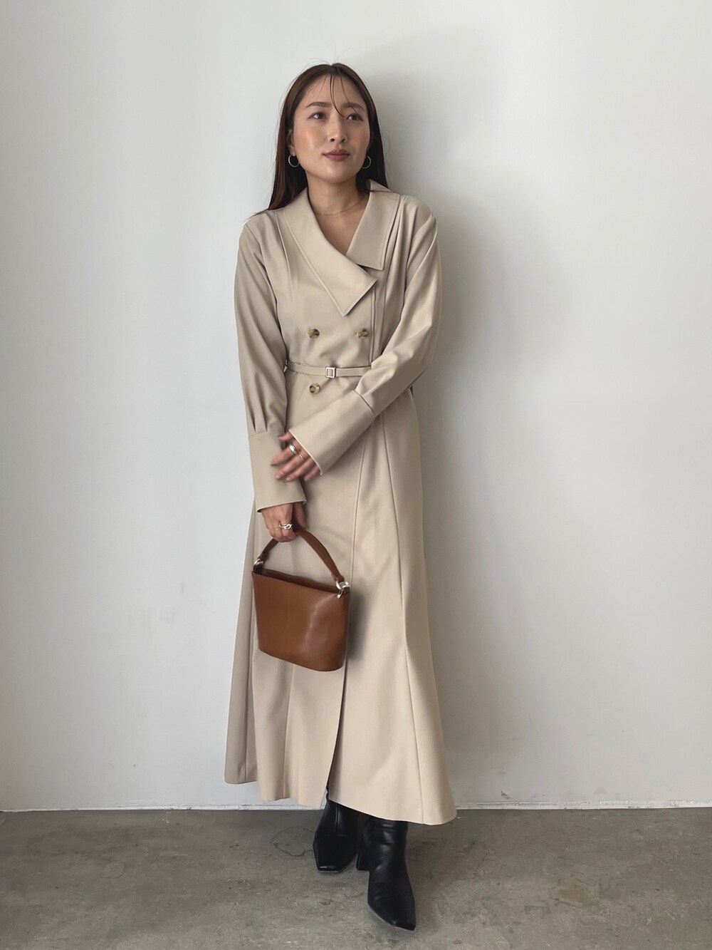 ブラック系のブーツ、ベージュ系のワンピース、イエロー系のハンドバッグを着用したレディースの秋コーディネートの3枚目の写真