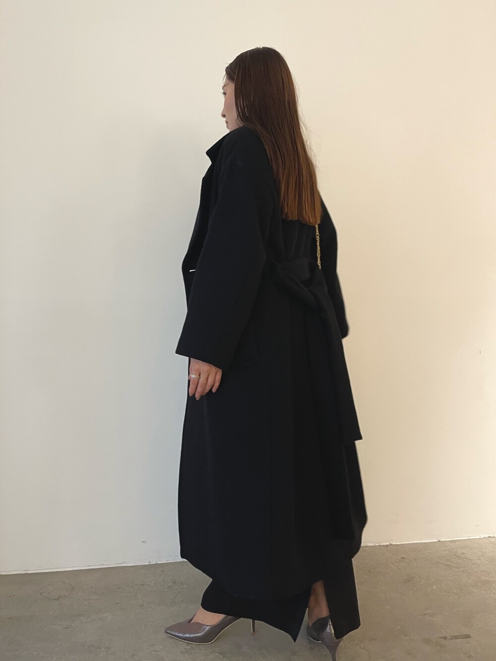 シルバー系のパンプス、ブラック系のハンドバッグ、ブラック系のドレスを着用したレディースの秋コーディネートの4枚目の写真