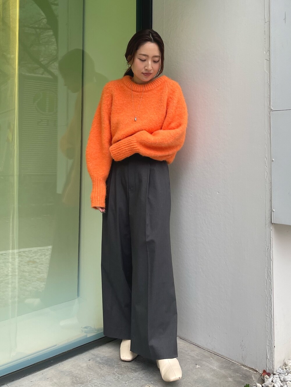 オレンジ系のニット/セーター、グレー系のその他パンツ、ホワイト系のブーツを着用したレディースの冬コーディネートの3枚目の写真