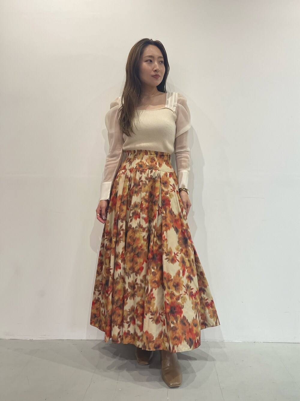 ベージュ系のブーツ、オレンジ系のスカート、ホワイト系のニット/セーターを着用したレディースの秋コーディネートの3枚目の写真