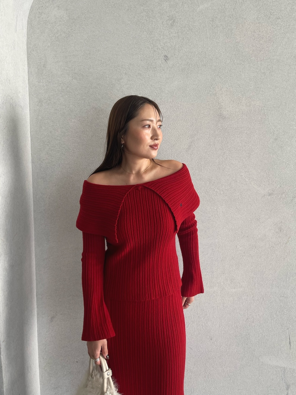 レッド系のニット/セーター、ベージュ系のブーツ、レッド系のスカートを着用したレディースの秋コーディネートの9枚目の写真