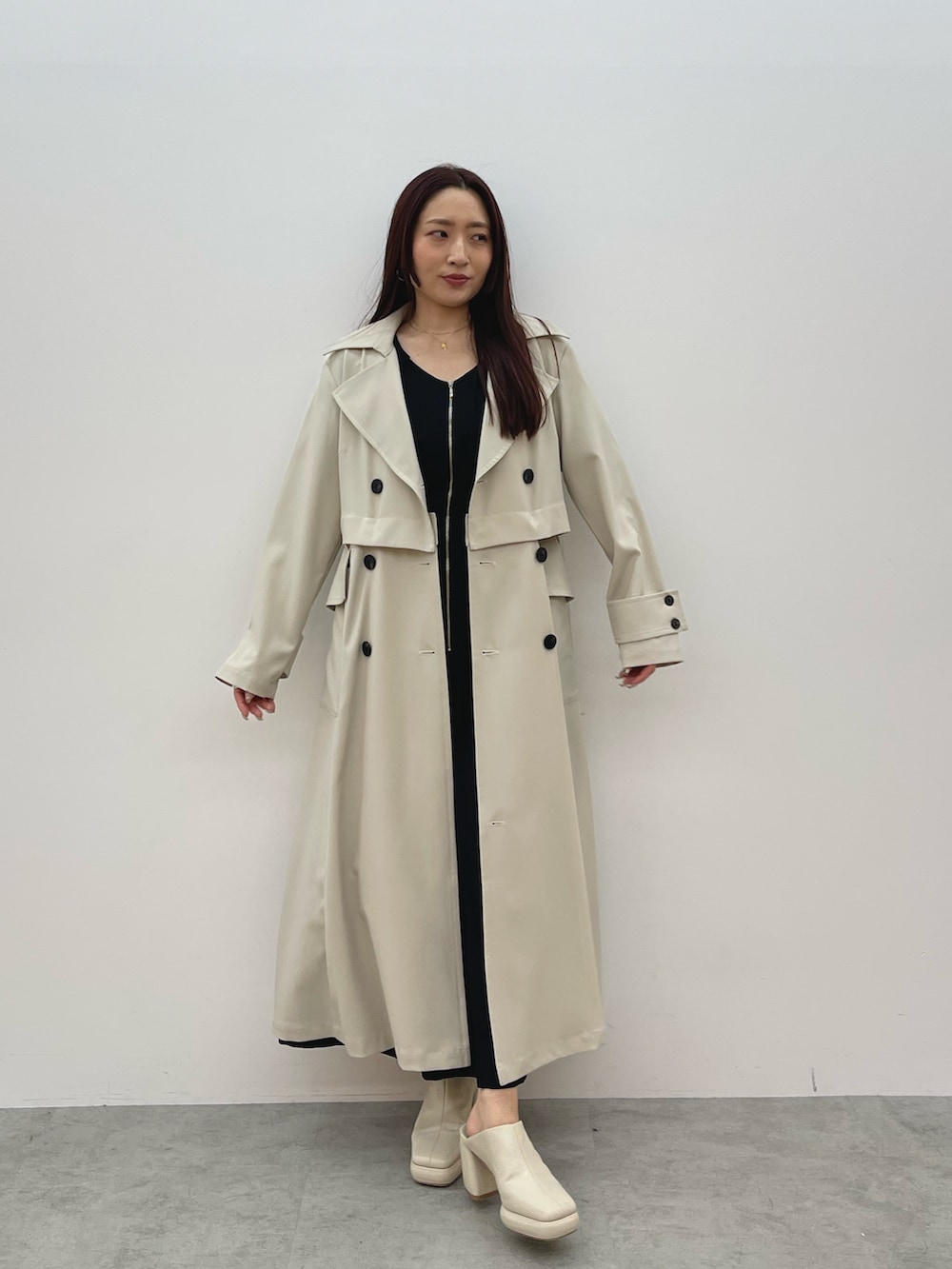 ホワイト系のトレンチコート、ブラック系のワンピース、ホワイト系のサンダルを着用したレディースの春コーディネートの3枚目の写真