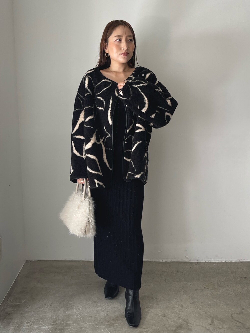 ブラック系のブーツ、ホワイト系のボストンバッグ、ブラック系のブルゾンを着用したレディースの秋コーディネートの2枚目の写真