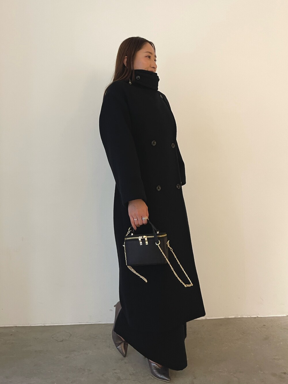 シルバー系のパンプス、ブラック系のハンドバッグ、ブラック系のドレスを着用したレディースの秋コーディネートの7枚目の写真