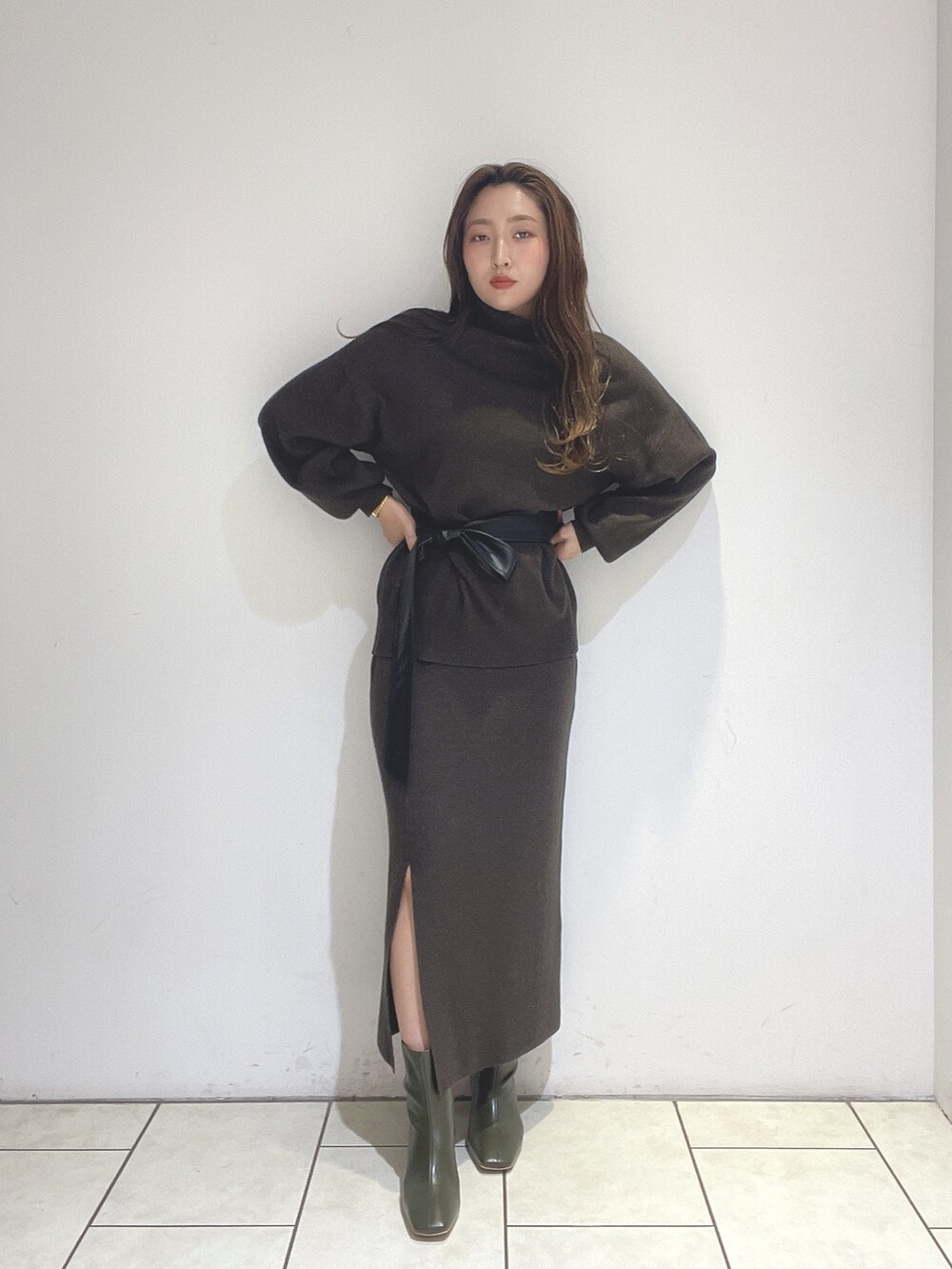 ブラウン系のニット/セーター、ブラウン系のスカート、グリーン系のブーツを着用したレディースの冬コーディネートの8枚目の写真