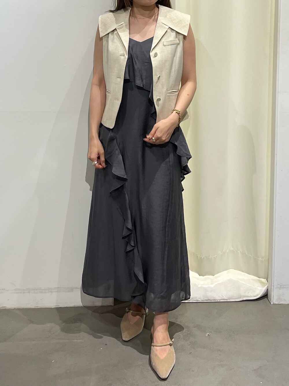 ホワイト系のベスト、グレー系のワンピース、ベージュ系のパンプスを着用したレディースの夏コーディネートの5枚目の写真