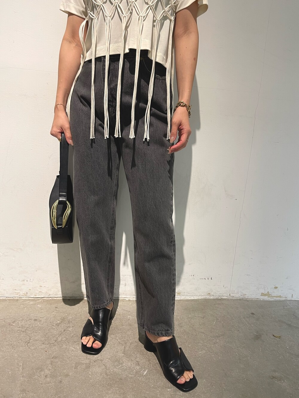 ブラック系のデニムパンツ、ブラック系のサンダル、ブラック系のショルダーバッグを着用したレディースの春コーディネートの6枚目の写真