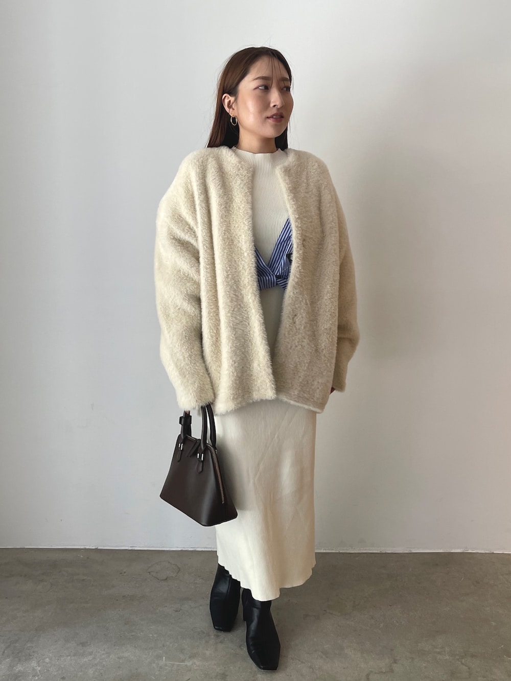 ブラウン系のボストンバッグ、ブラック系のブーツ、ホワイト系のワンピースを着用したレディースの秋コーディネートの3枚目の写真