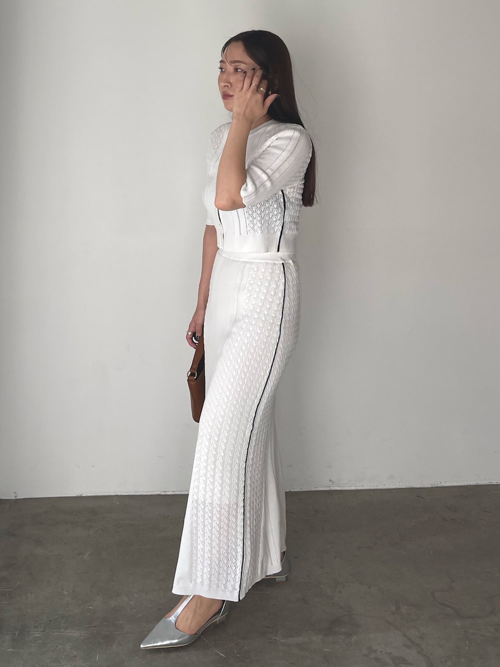 イエロー系のハンドバッグ、シルバー系のパンプス、ホワイト系のワンピースを着用したレディースの冬コーディネートの6枚目の写真