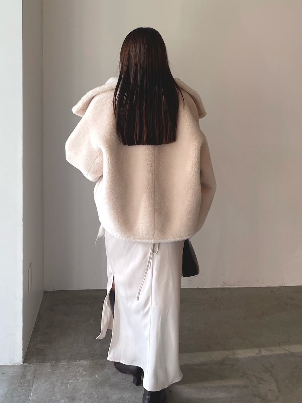 ベージュ系のワンピース、ブラウン系のハンドバッグ、ブラウン系のブーツを着用したレディースの冬コーディネートの6枚目の写真