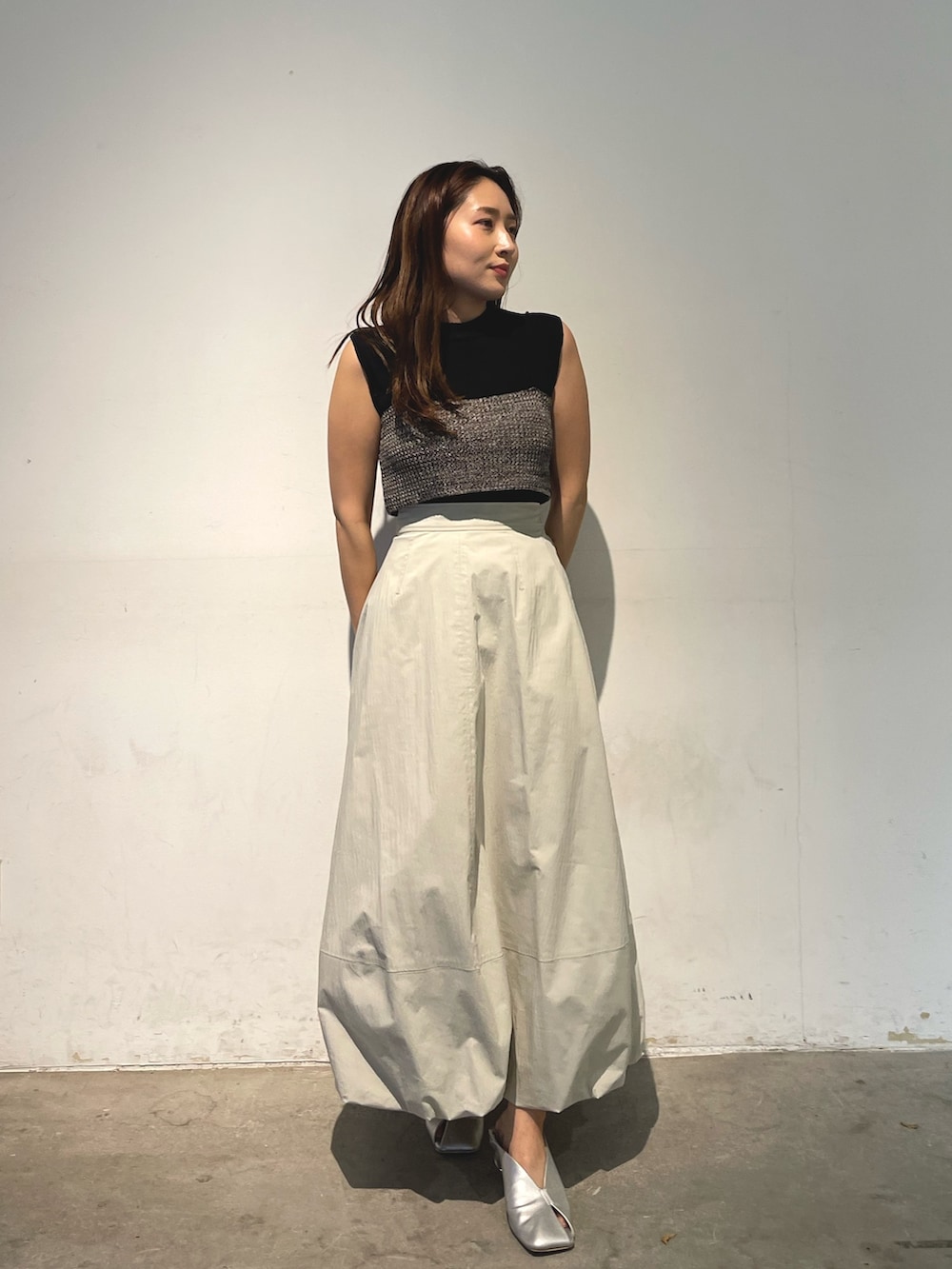 シルバー系のパンプス、ブラック系のニット/セーター、ホワイト系のスカートを着用したレディースの春コーディネートの4枚目の写真