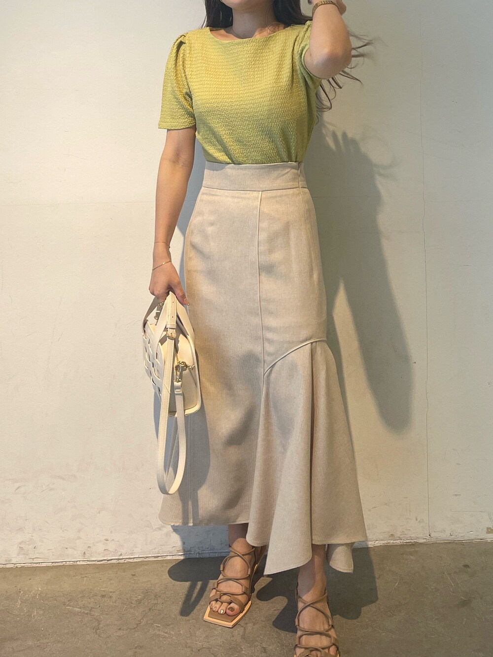 グリーン系のTシャツ/カットソー、ベージュ系のサンダル、ホワイト系のスカートを着用したレディースの春コーディネートの3枚目の写真