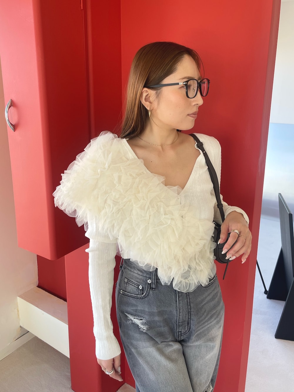 オレンジ系のサンダル、グレー系のデニムパンツ、ホワイト系のカーディガン/ボレロを着用したレディースの春コーディネートの8枚目の写真