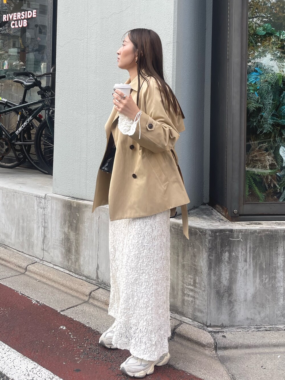 ホワイト系のワンピース、ベージュ系のトレンチコート、ゴールド系のピアス（両耳用）を着用したレディースの冬コーディネートの2枚目の写真