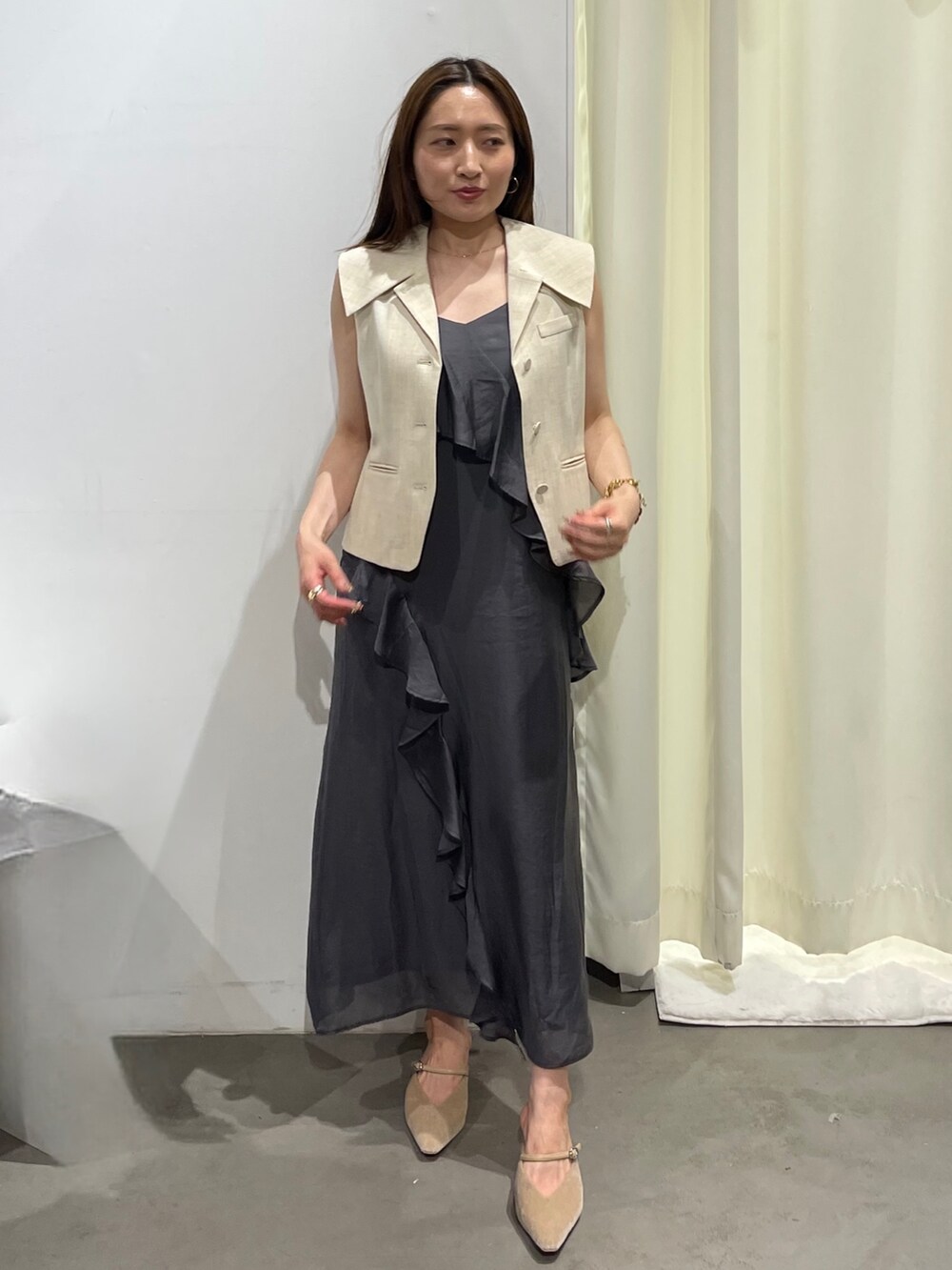 ホワイト系のベスト、グレー系のワンピース、ベージュ系のパンプスを着用したレディースの夏コーディネートの3枚目の写真