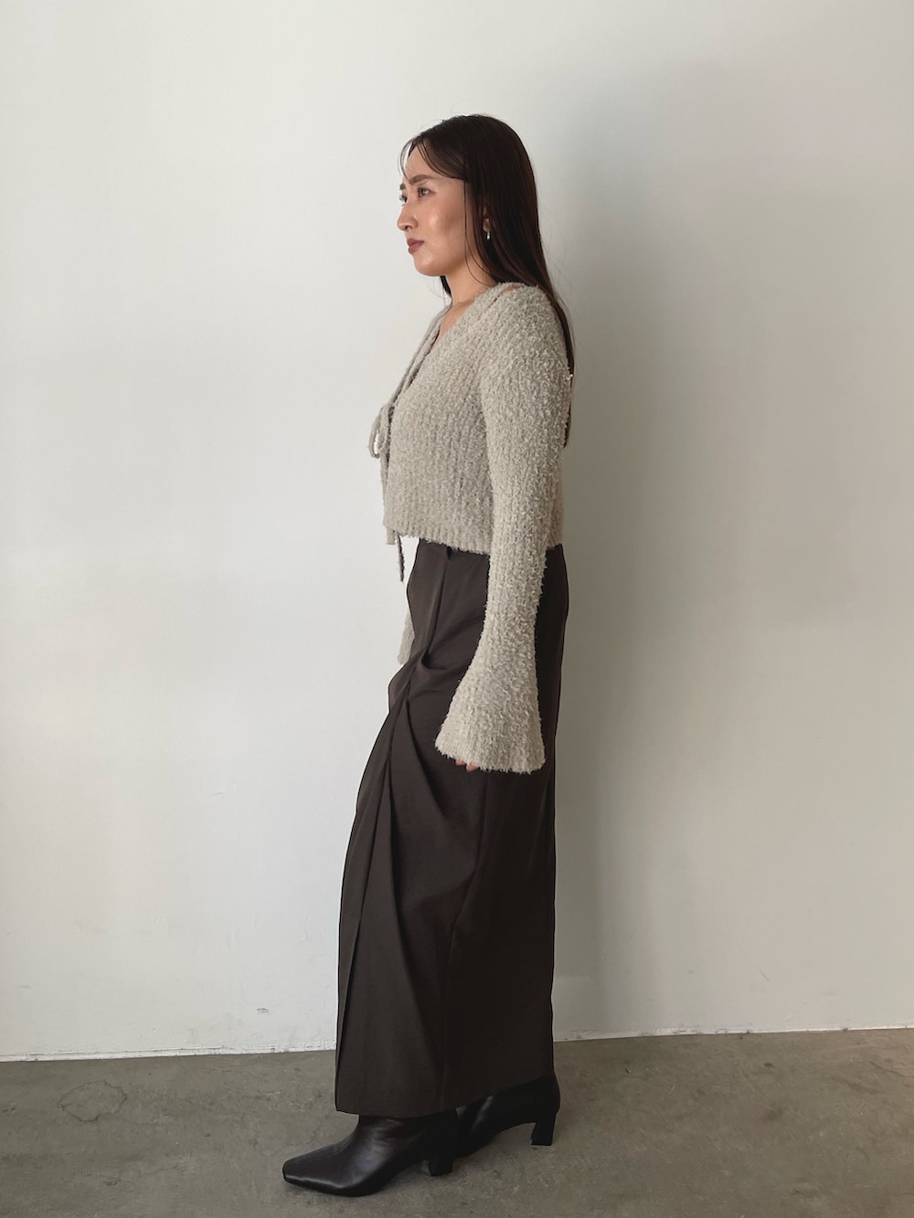 グレー系のアンサンブル、イエロー系のハンドバッグ、ブラウン系のスカートを着用したレディースの秋コーディネートの7枚目の写真