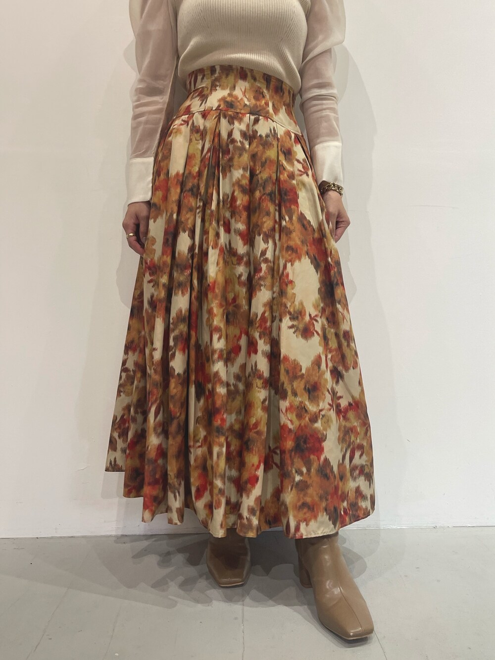 ベージュ系のブーツ、オレンジ系のスカート、ホワイト系のニット/セーターを着用したレディースの秋コーディネートの7枚目の写真