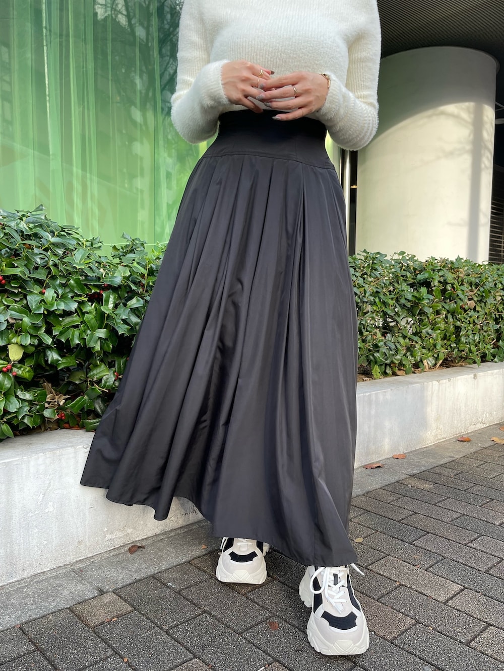 ブラック系のスニーカー、ホワイト系のニット/セーター、ブラック系のスカートを着用したレディースの冬コーディネートの6枚目の写真