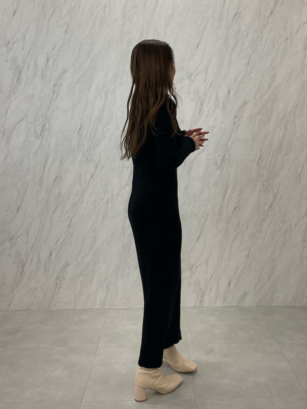 ブラック系のワンピース、ホワイト系のブーツ、ゴールド系のネックレスを着用したレディースの冬コーディネートの4枚目の写真