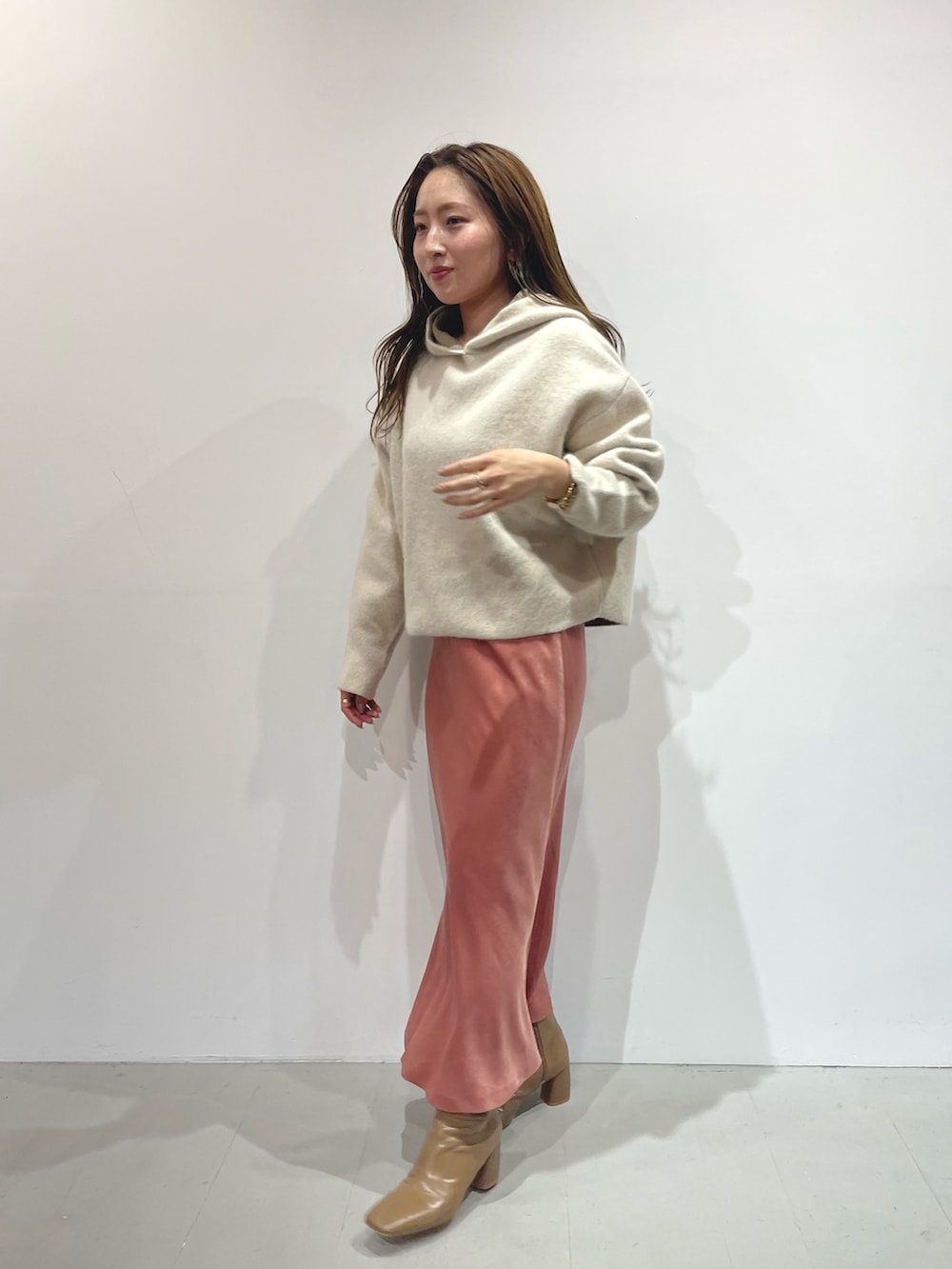 ピンク系のスカート、ベージュ系のブーツ、ホワイト系のパーカーを着用したレディースの夏コーディネートの2枚目の写真
