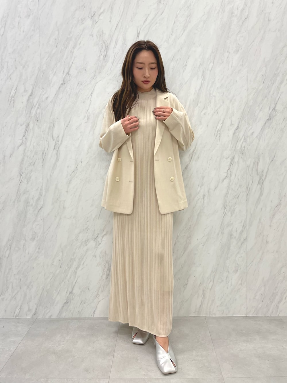 シルバー系のパンプス、ベージュ系のテーラードジャケット、ホワイト系のワンピースを着用したレディースの春コーディネートの2枚目の写真