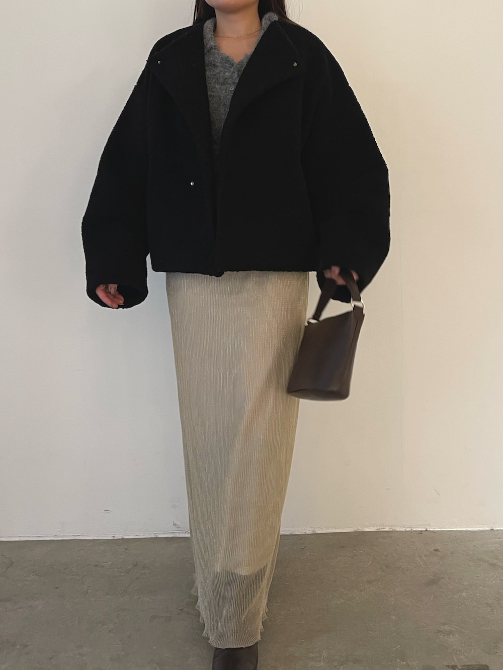 ブラック系のブルゾン、ブラウン系のハンドバッグ、ブラウン系のブーツを着用したレディースの秋コーディネートの5枚目の写真