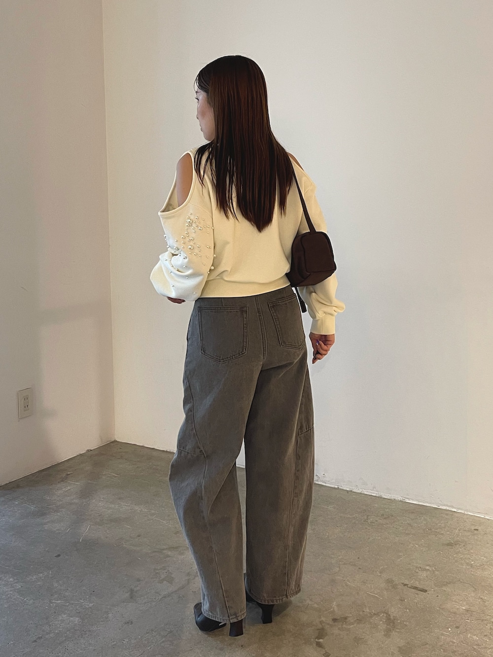 グレー系のデニムパンツ、ブラック系のブーツ、ブラウン系のハンドバッグを着用したレディースの秋コーディネートの5枚目の写真