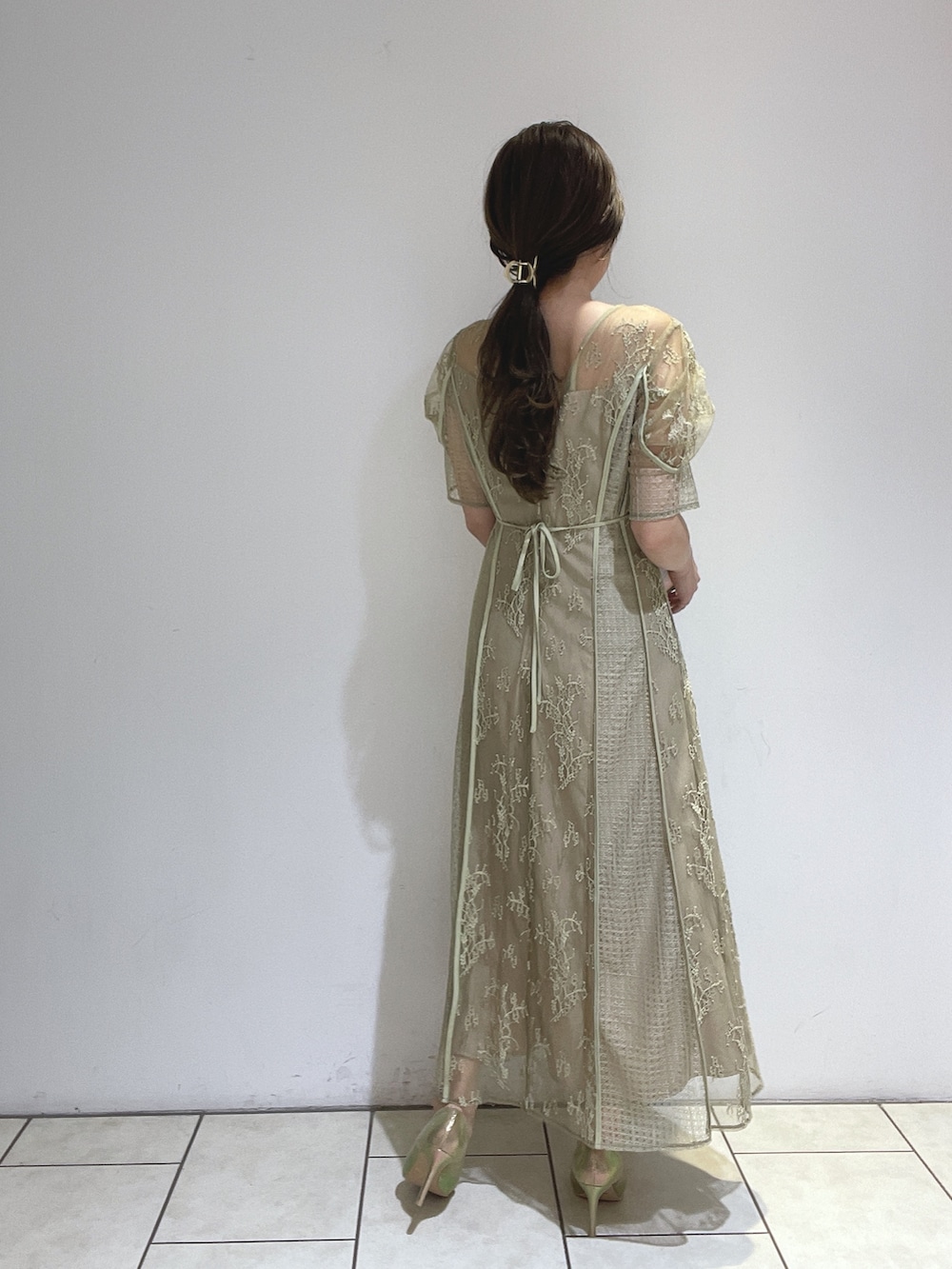 ゴールド系のハンドバッグ、グリーン系のドレス、ゴールド系のパンプスを着用したレディースの冬コーディネートの7枚目の写真