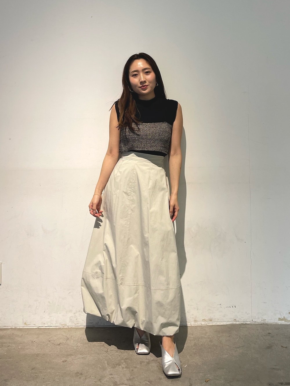 シルバー系のパンプス、ブラック系のニット/セーター、ホワイト系のスカートを着用したレディースの春コーディネートの2枚目の写真
