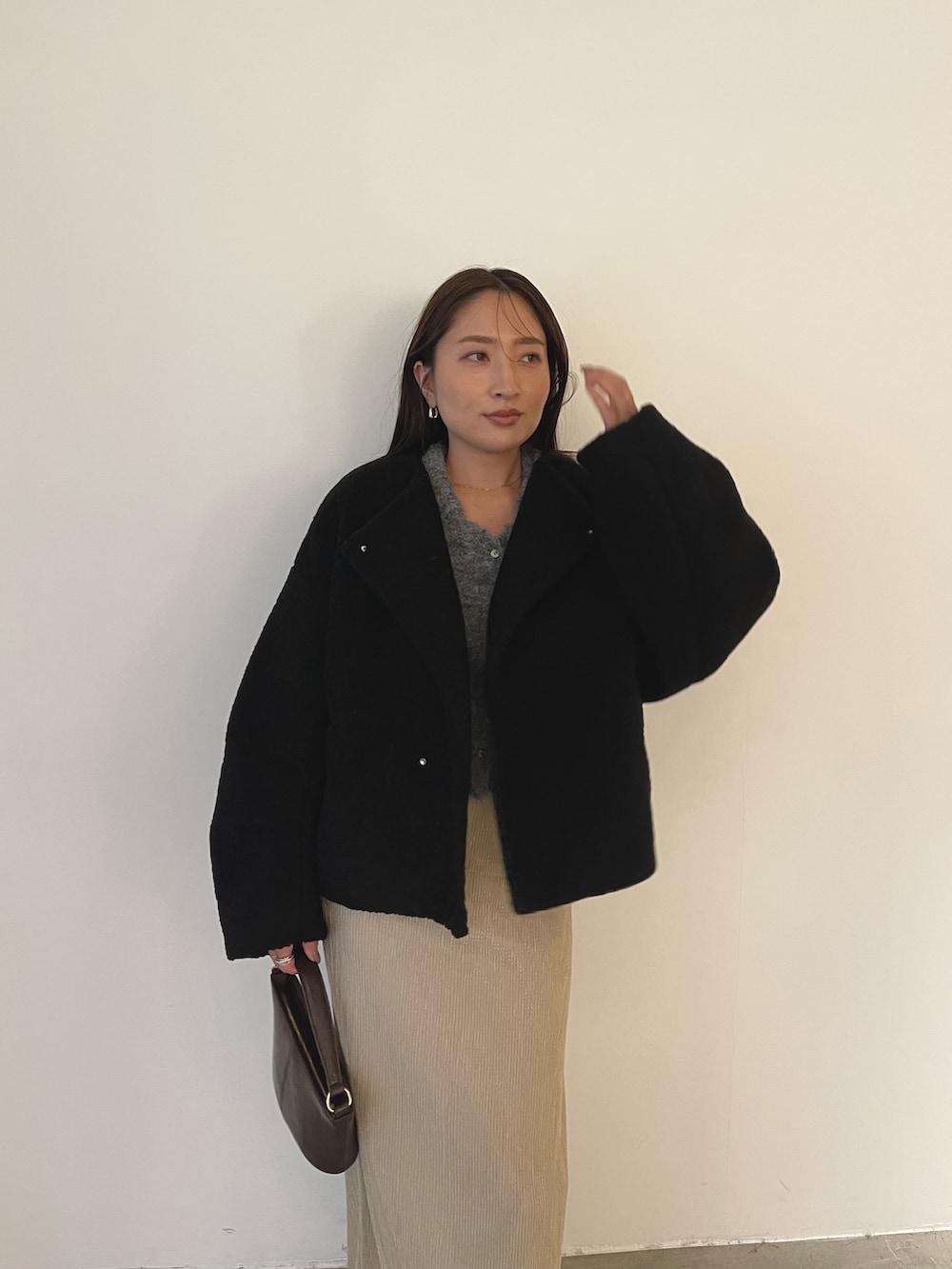 ブラック系のブルゾン、ブラウン系のハンドバッグ、ブラウン系のブーツを着用したレディースの秋コーディネートの7枚目の写真