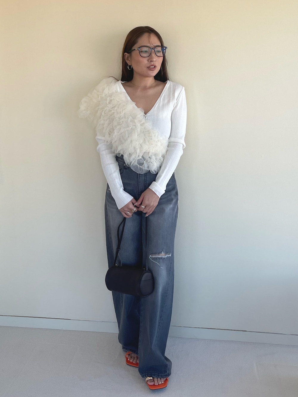 オレンジ系のサンダル、グレー系のデニムパンツ、ホワイト系のカーディガン/ボレロを着用したレディースの春コーディネートの3枚目の写真