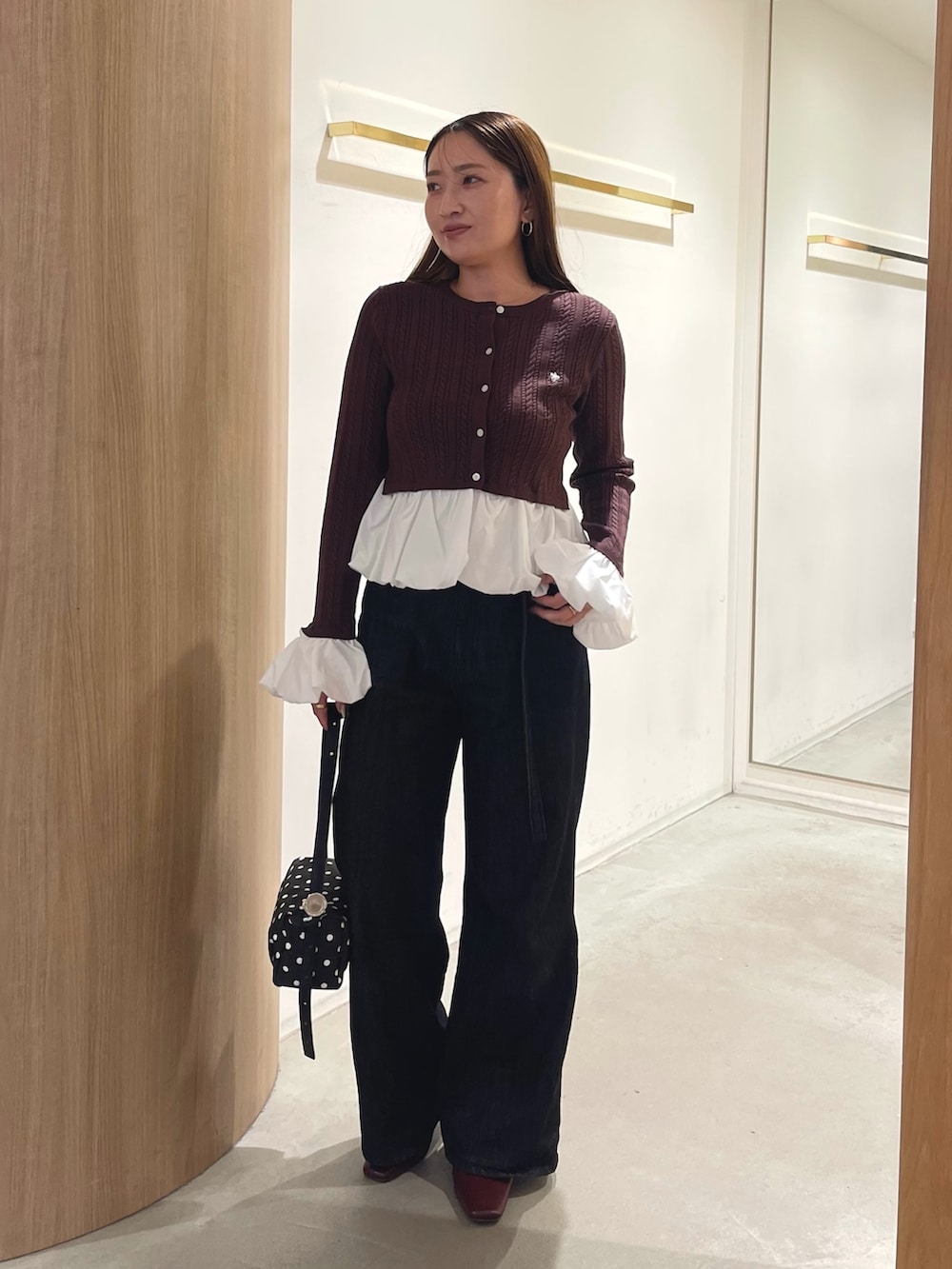 レッド系のブーツ、ブラック系のデニムパンツ、ブラック系のハンドバッグを着用したレディースの秋コーディネートの5枚目の写真