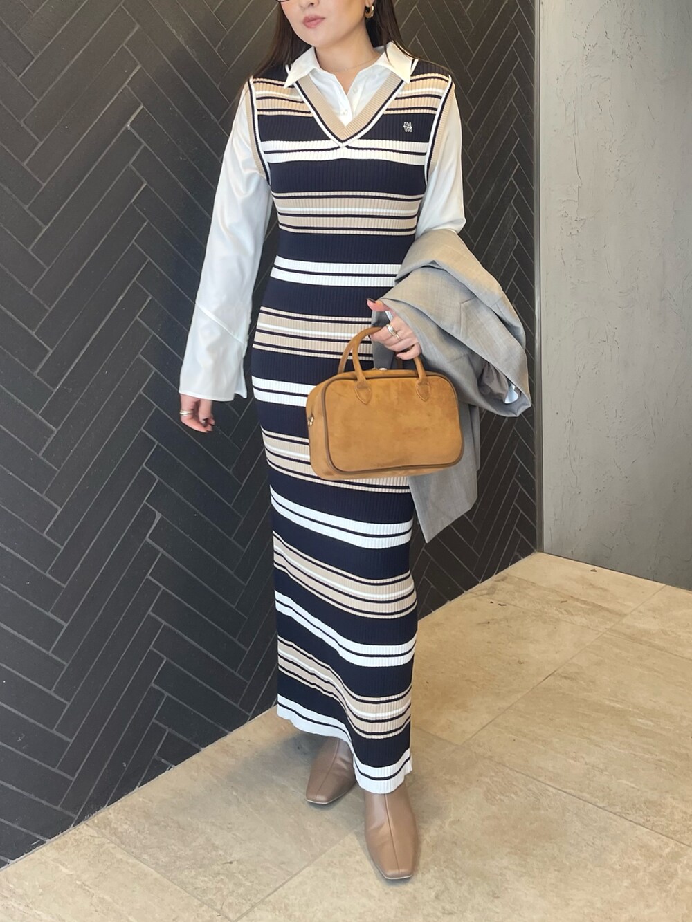 イエロー系のハンドバッグ、ベージュ系のブーツ、グレー系のテーラードジャケットを着用したレディースの冬コーディネートの4枚目の写真