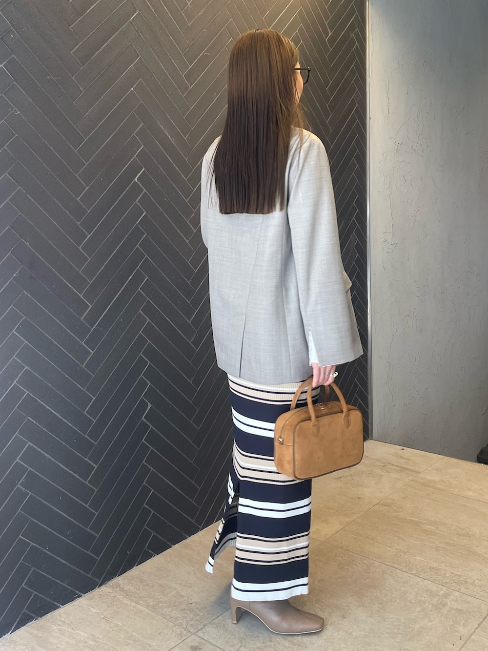 イエロー系のハンドバッグ、ベージュ系のワンピース、グレー系のテーラードジャケットを着用したレディースの冬コーディネートの5枚目の写真