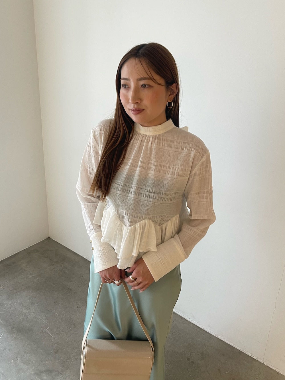 シルバー系のパンプス、ホワイト系のシャツ/ブラウス、グリーン系のスカートを着用したレディースの冬コーディネートの9枚目の写真