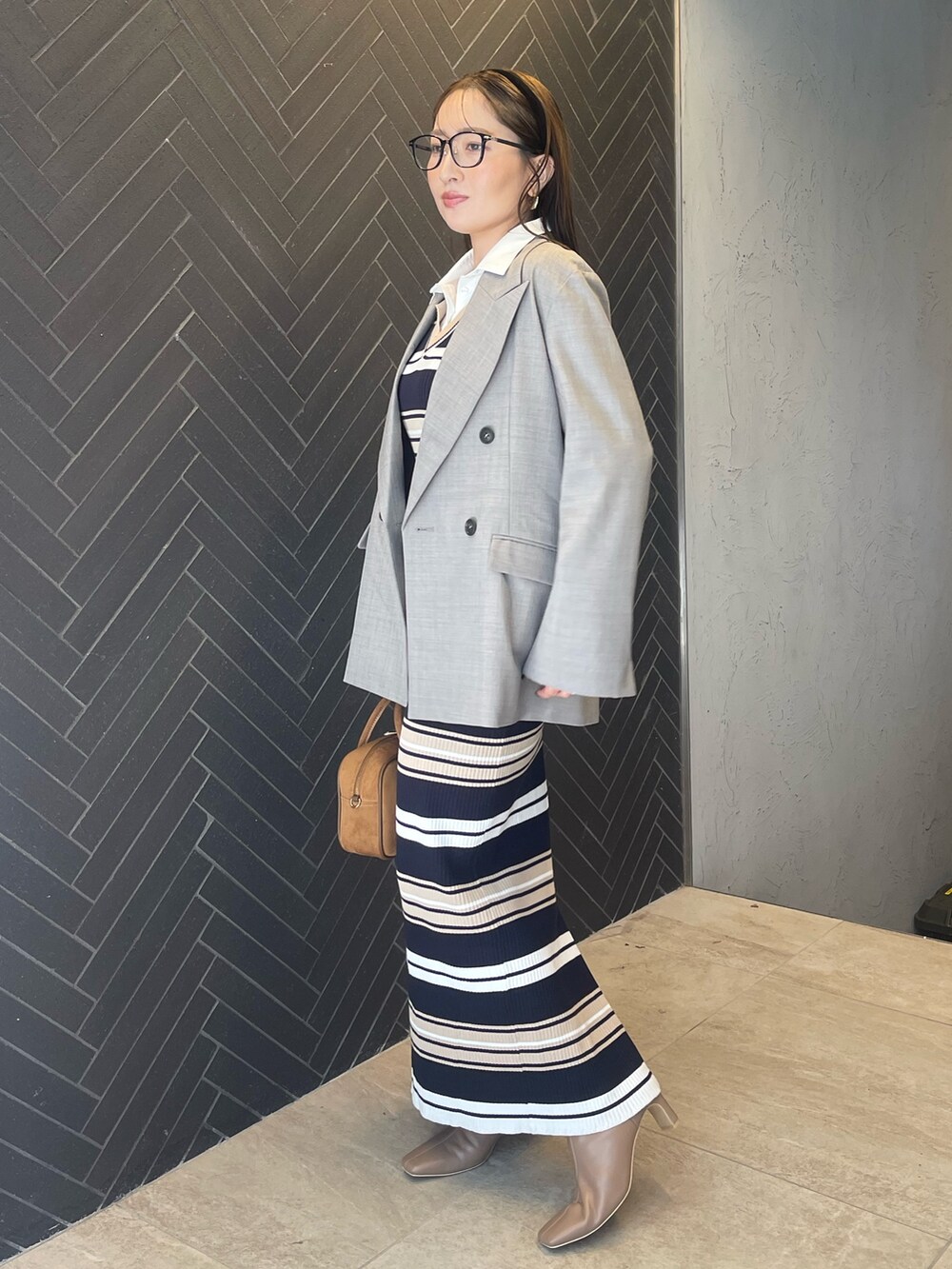 イエロー系のハンドバッグ、ベージュ系のワンピース、グレー系のテーラードジャケットを着用したレディースの冬コーディネートの4枚目の写真