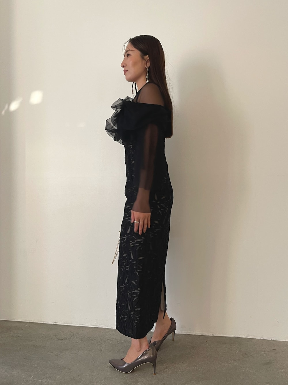 シルバー系のパンプス、ブラック系のハンドバッグ、ブラック系のドレスを着用したレディースの秋コーディネートの6枚目の写真